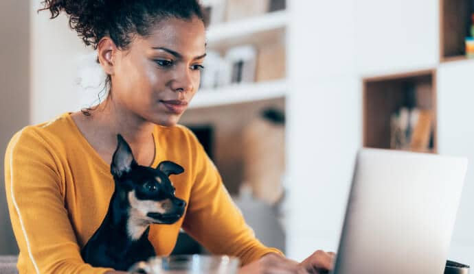 Donna che usa il computer portatile mentre il cane le siede in grembo