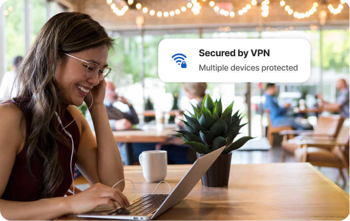 Donna in un bar che ride mentre guarda lo schermo di un laptop